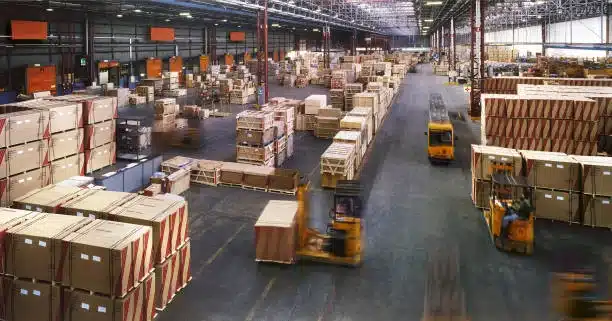 Wide view of large distribution warehouse with forklifts moving pallets.