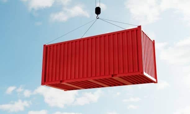 Red container lifted by port crane, representing handling of consolidated LCL cargo.