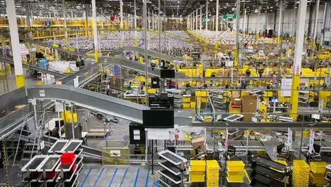 Fulfillment center filled with workers and conveyor belts processing orders.